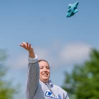 A player throws a bag and and watches it fly through the sky
